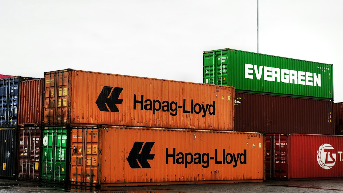 Stacked shipping containers from Hapag-Lloyd and Evergreen at a container yard | UCL Barcelona vs PSG