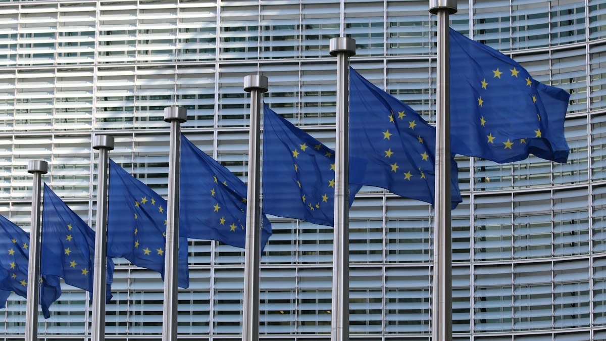 A row of European Union flags in front of a modern glass building | Champions League