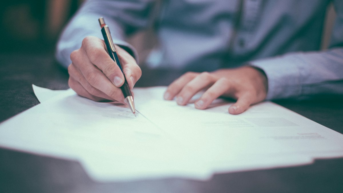 A person signing printed documents at a desk | Diwali 2026