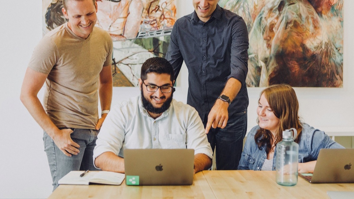 A team gathered around a laptop in an office